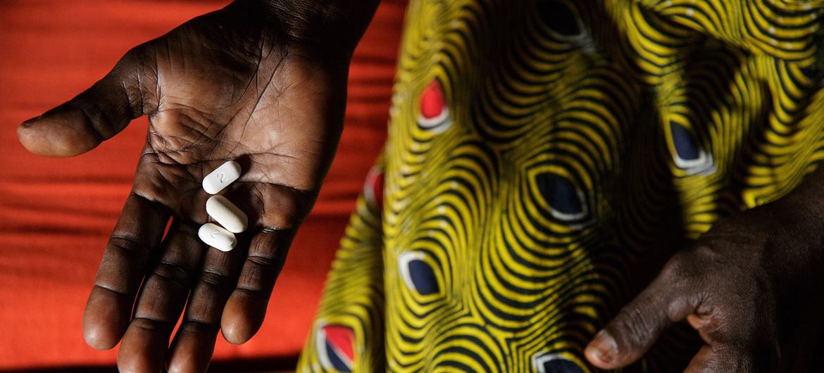 In Côte d’Ivoire, a woman living with HIV holds three pills she takes daily as part of antiretroviral therapy.