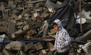 A boy walks thoughtfully as he inspects the rubble of destroyed houses in the city of Rafah, southern Gaza Strip.
