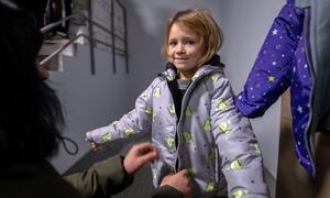 A 4-year-old girl in Izium, Ukraine, tries on a jacket provided by UNICEF and partners.