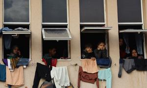On 11 January 2024, internally displaced people look through the window at a shelter centre in Al-Quds Open University.