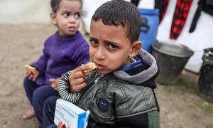 Displaced children eat high energy biscuits at a makeshift shelter in central Gaza.