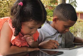 Two Venezuelan children use tablets at school.