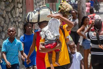 Displaced by escalating violence, families in Haiti carry their belongings as they flee their homes in search of safety. 