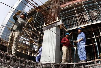 Migrant workers transport metal rods on a construction site in Qatar.