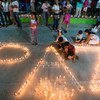 Women and children from the Mocoa community in Colombia light candles forming the word peace.